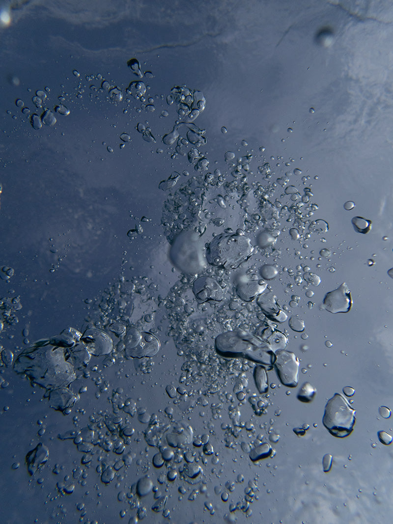 Bubbles moving rapidly across the frame in crystal clear open water