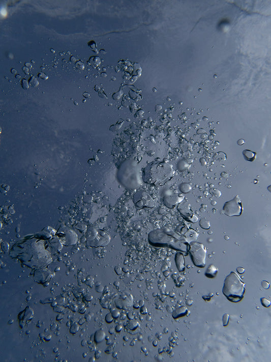 Bubbles moving rapidly across the frame in crystal clear open water