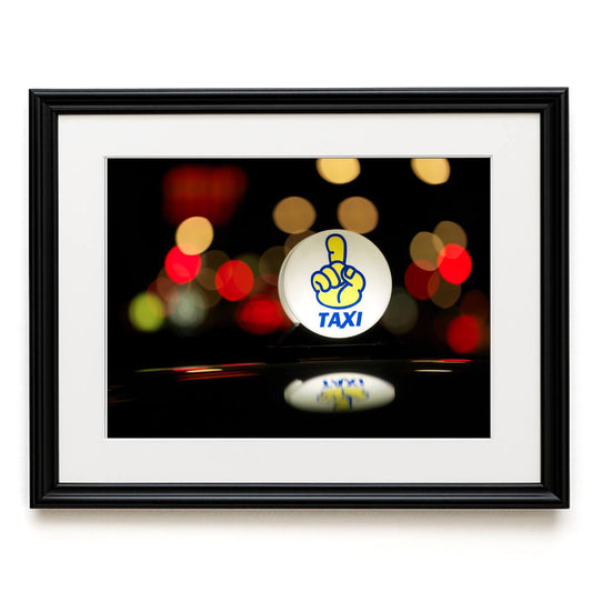 Framed picture of a taxi sign with blurred lights in the background